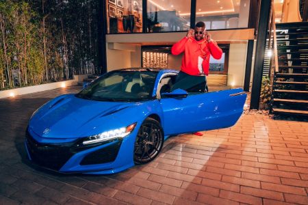 Winston Duke strikes for a pose with his blue car.